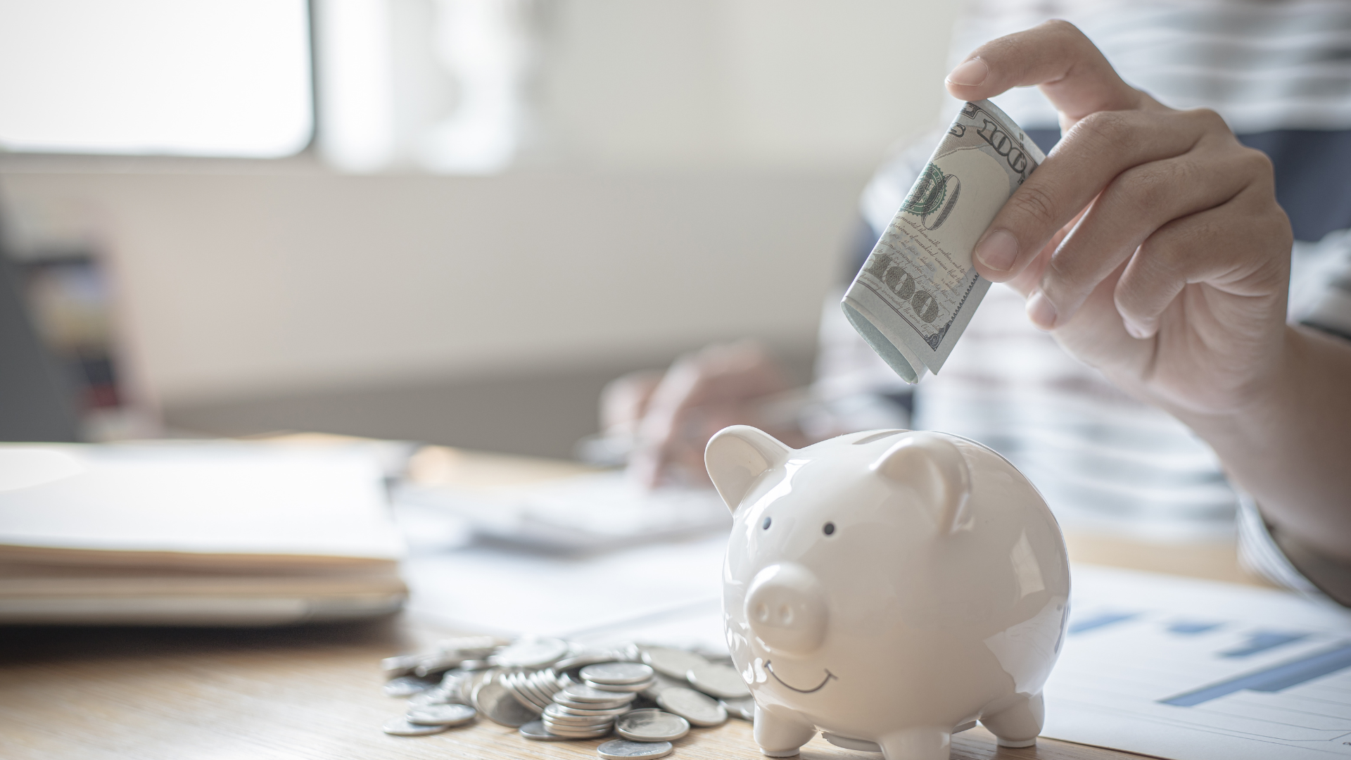 Person putting mony in a pig shaped bank